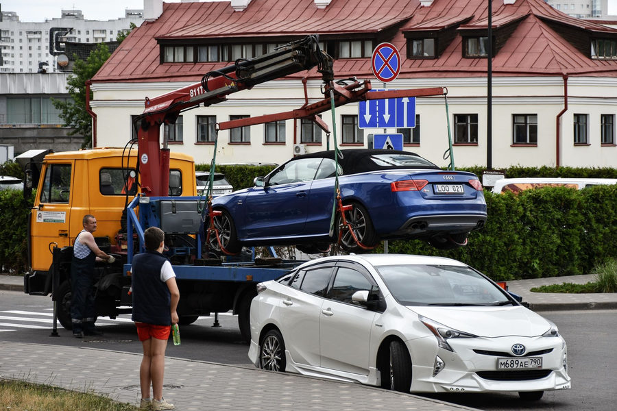 Blue car being towed for emergency with bystanders watching